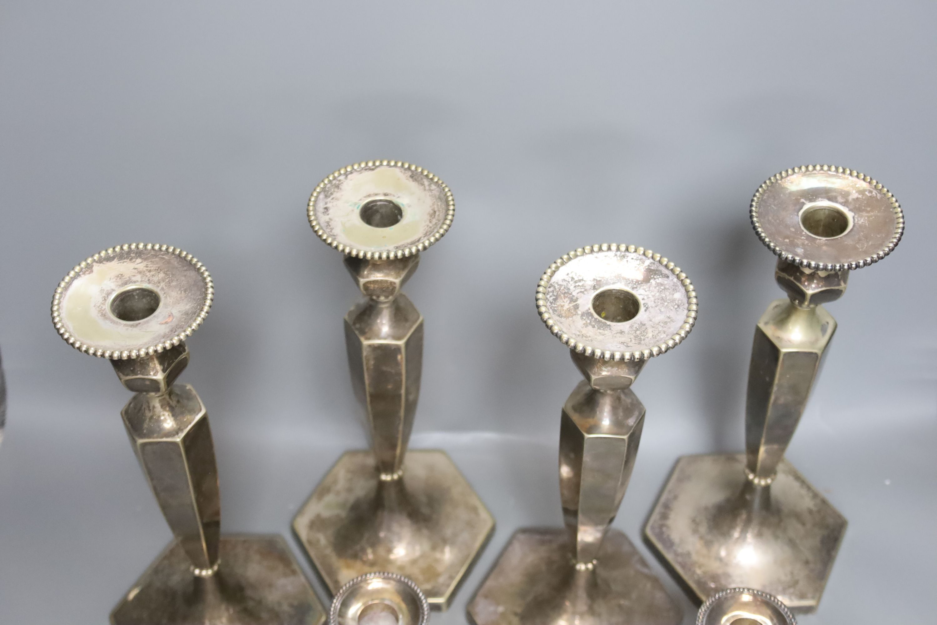 A set of 4 silver plated candlesticks and a pair of plated dwarf candlesticks